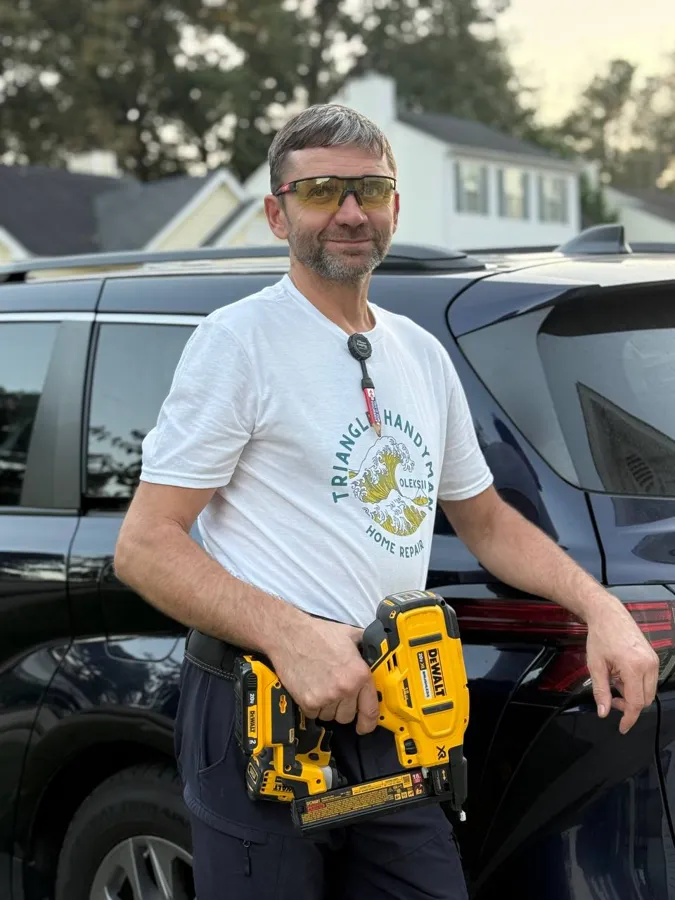 Triangle Handyman in a company shirt with a cordless nailer, ready for the next job