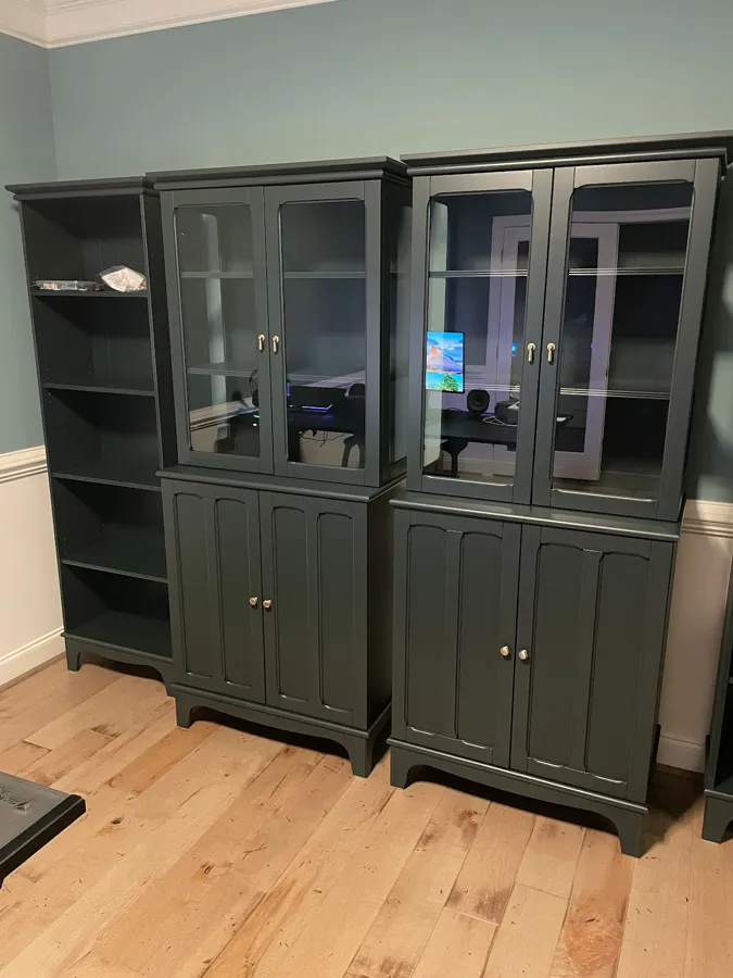 Pair of dark green glass-door cabinets assembled and set in a home office