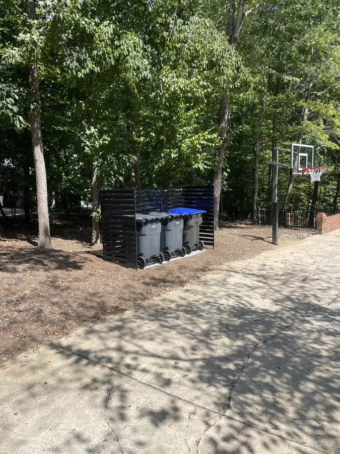 Trash can enclosure and privacy screen beside a driveway