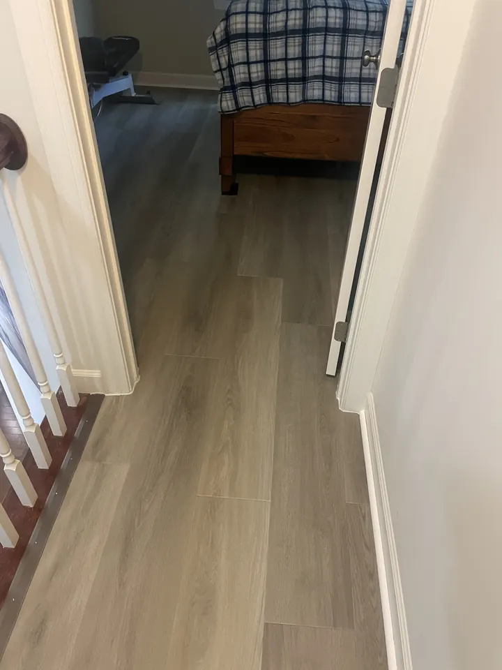 New gray plank flooring running from the hallway into the bedroom