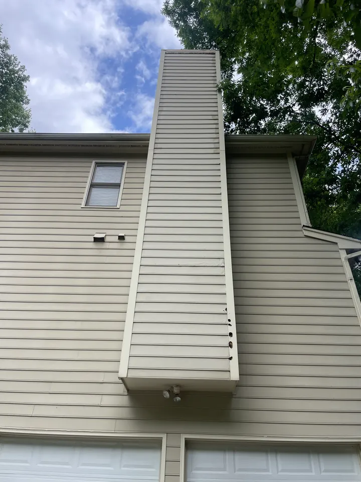 Two-story chimney chase with holes and damaged siding, before repair